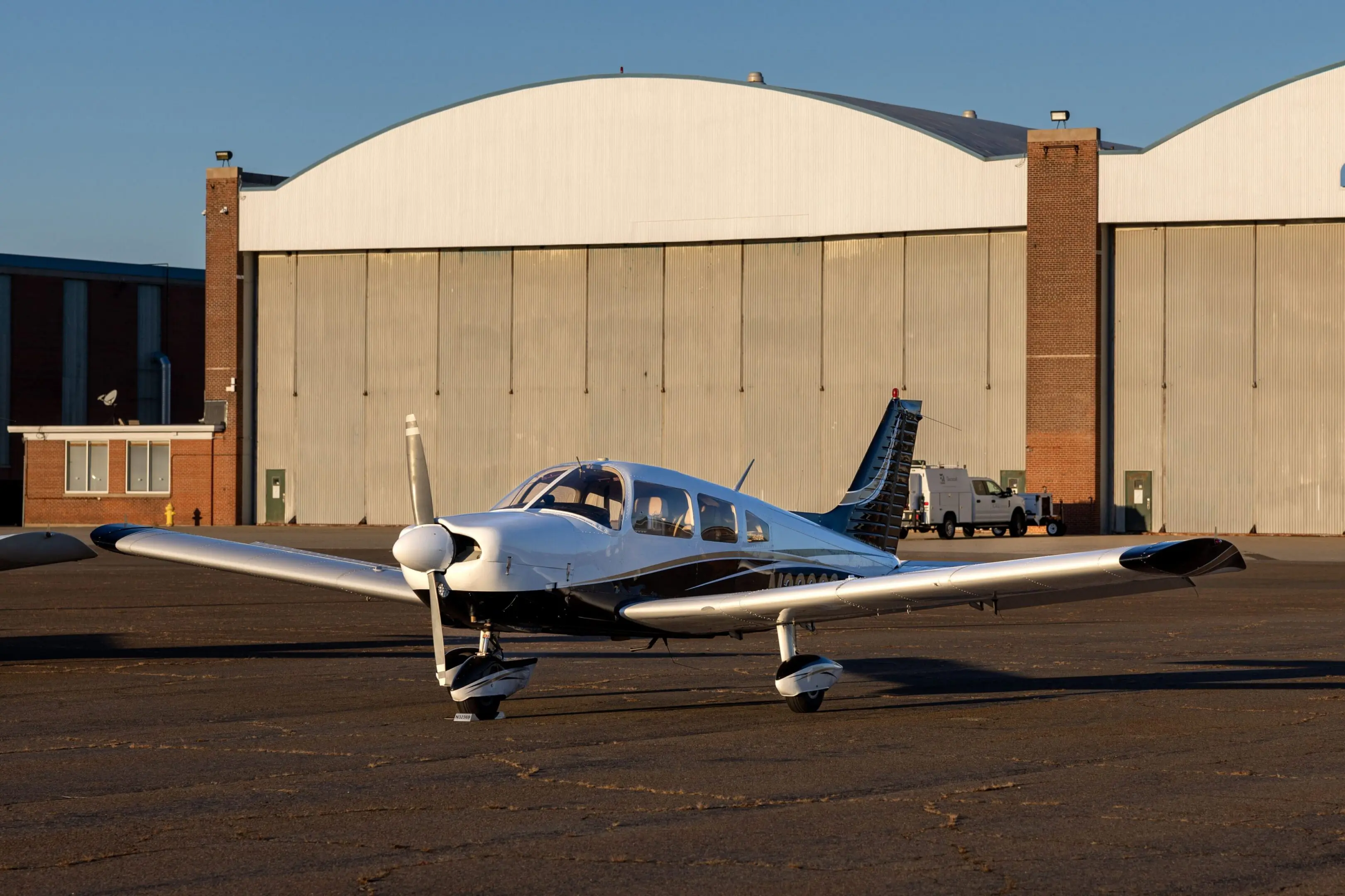 Small airplane parked in front of hangar.