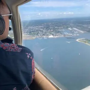 Man looking out small plane window over water.