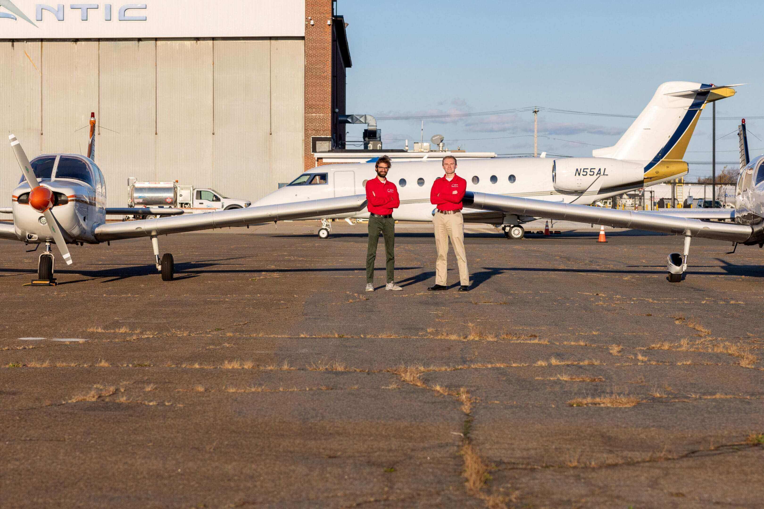 Two people standing between parked airplanes.