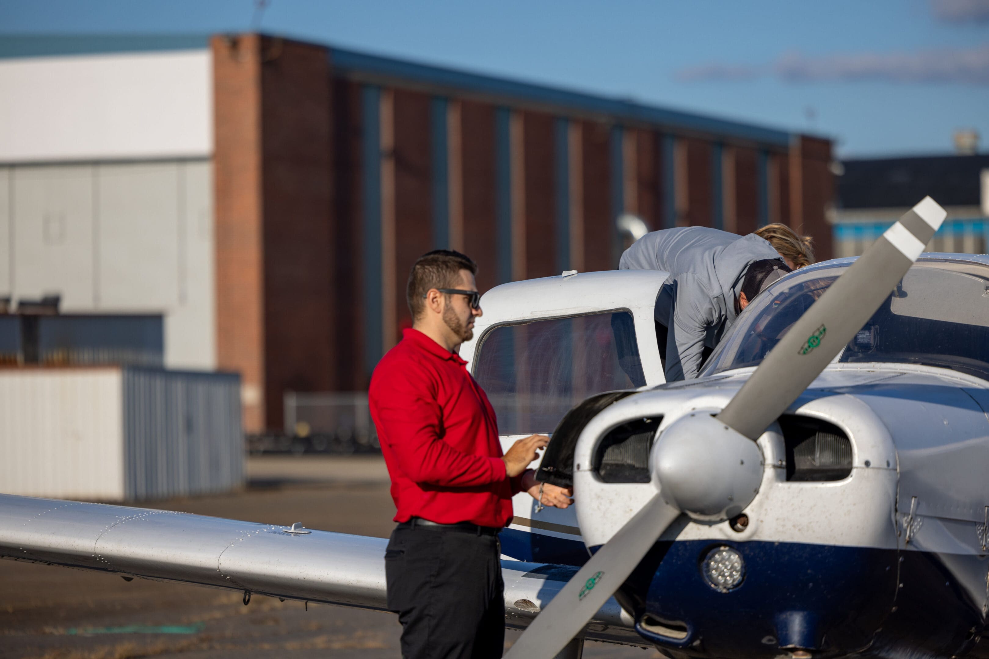 Man beside small airplane at airport.