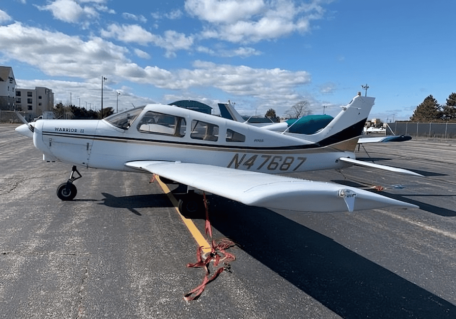 Small airplane parked on a sunny runway.