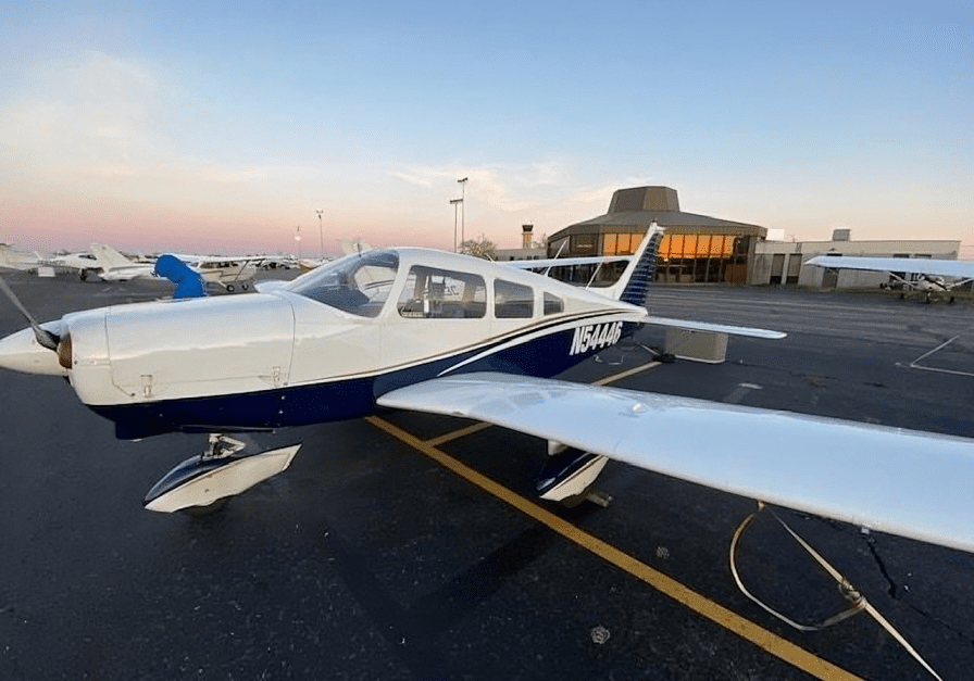 Small airplane parked at airport during sunset.