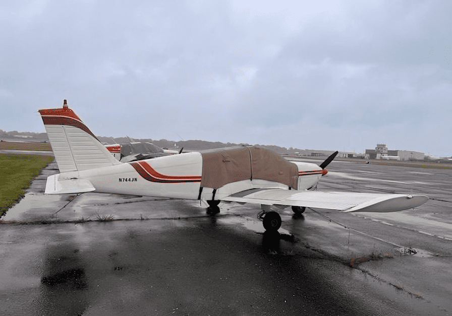 Small airplane parked on wet runway.
