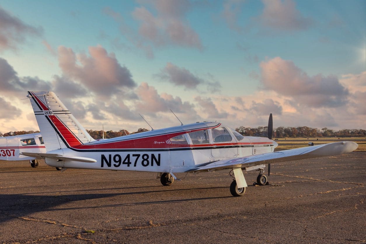 Small airplane on runway during sunset.