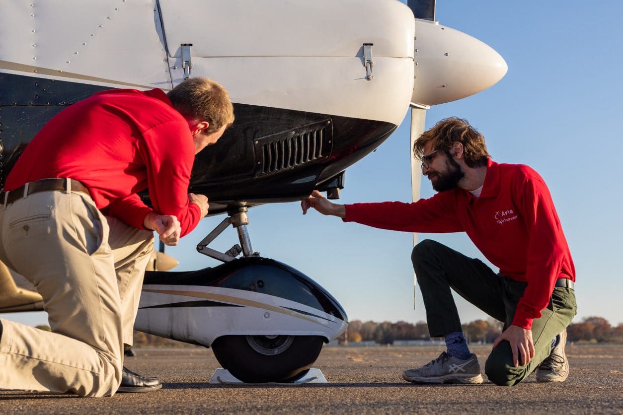 Two people inspecting small aircraft landing gear.