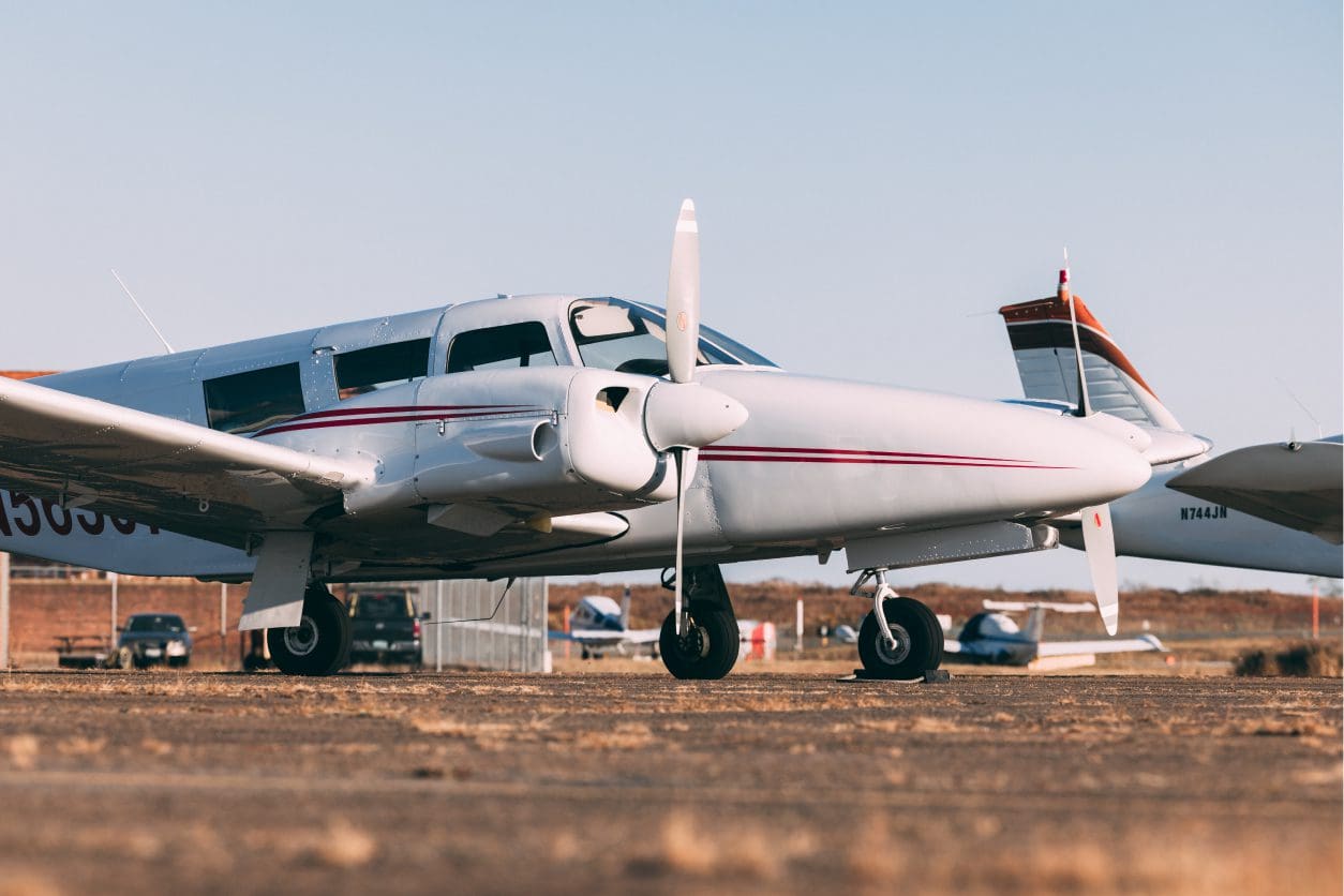 White twin-engine airplane parked on runway.