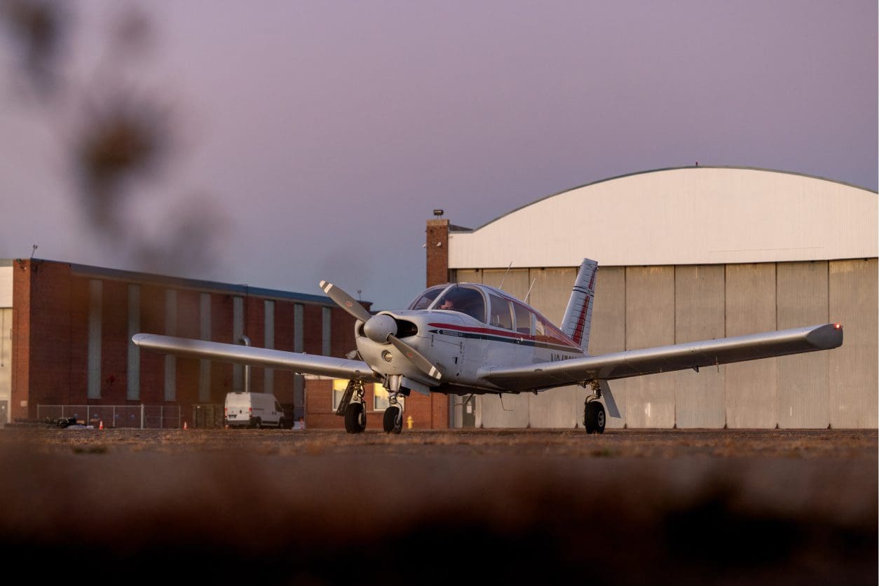 Small airplane parked near large hangar.