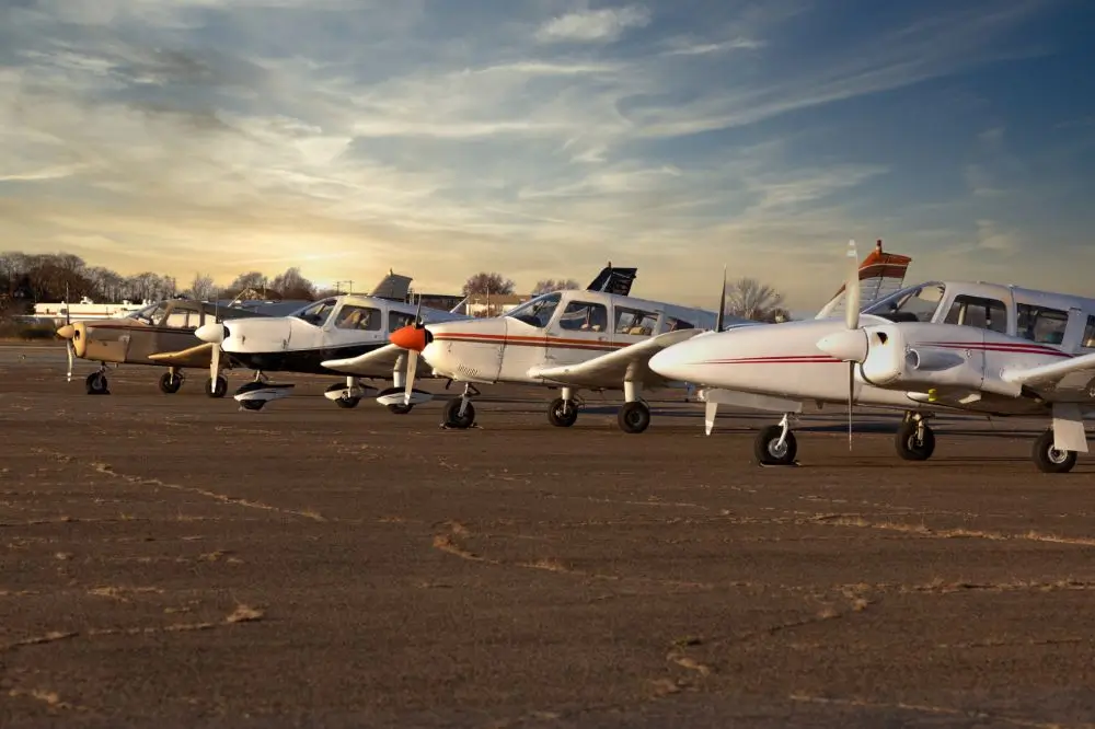 Small airplanes parked on runway at sunset.