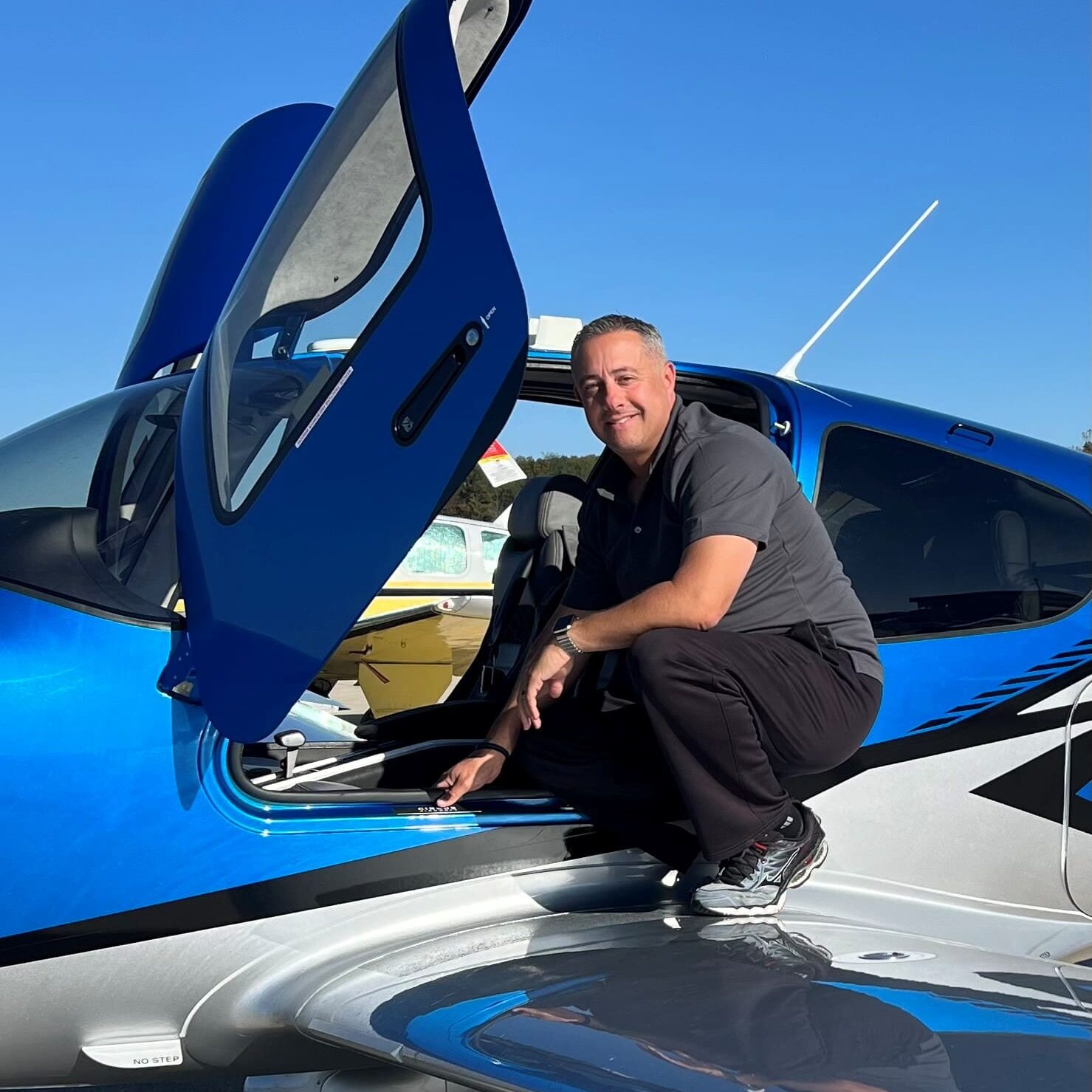 Smiling man inspecting small blue plane exterior