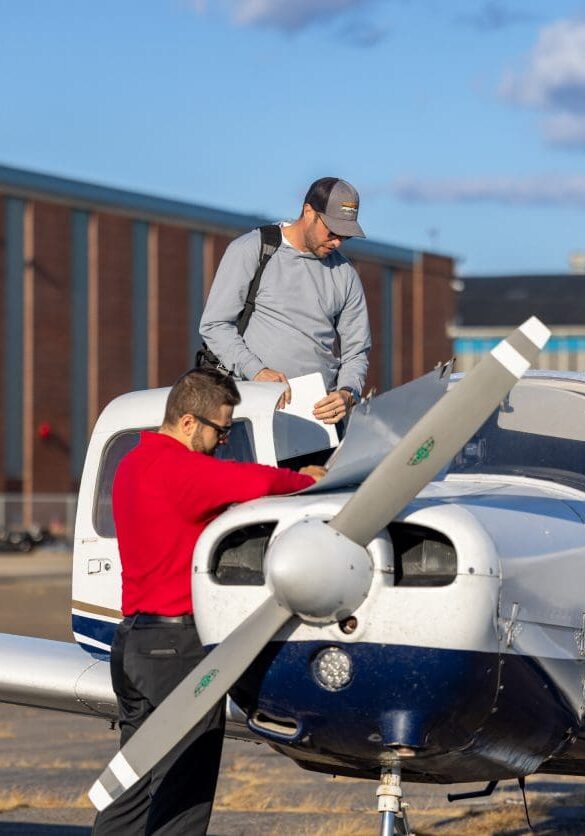 Two men inspecting a small airplane.